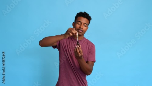 Man applying moisturizing serum to his face in studio.