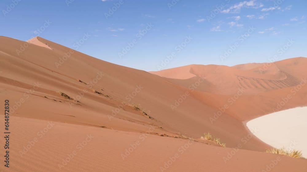 Dry clay pan with red desert sand dunes in Sossusvlei or Sesriem in Namibia. Namib Desert and Big Daddy dune in Deadvlei. Orange desert with blue sky with small clouds. 4K Cinematic footage. Dry clay pan with red desert sand dunes in Sossusvlei or Sesriem in Namibia. Namib Desert and Big Daddy dune in Deadvlei. Orange desert with blue sky with small clouds. 4K Cinematic footage.