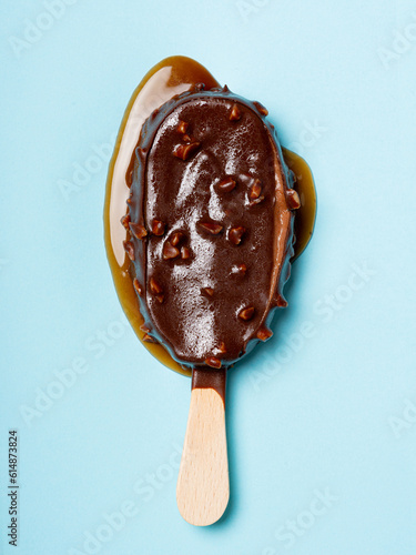 Melted chocolate and almonds stick ice cream isolated on cyan background
