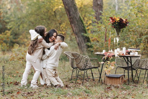 Mothers day. Happy young mother with teen daughter and little son are having fun and hugging outdoors in the autumn park. Family day. Idyllic stylish family having picnic on holiday. happy childhood. © Andriy Medvediuk