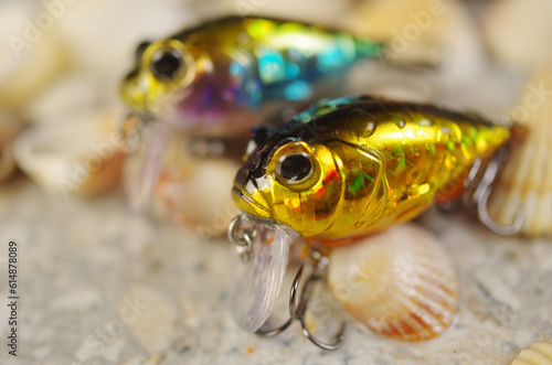 Two solid-bodied spinning baits against the background of sea stones.