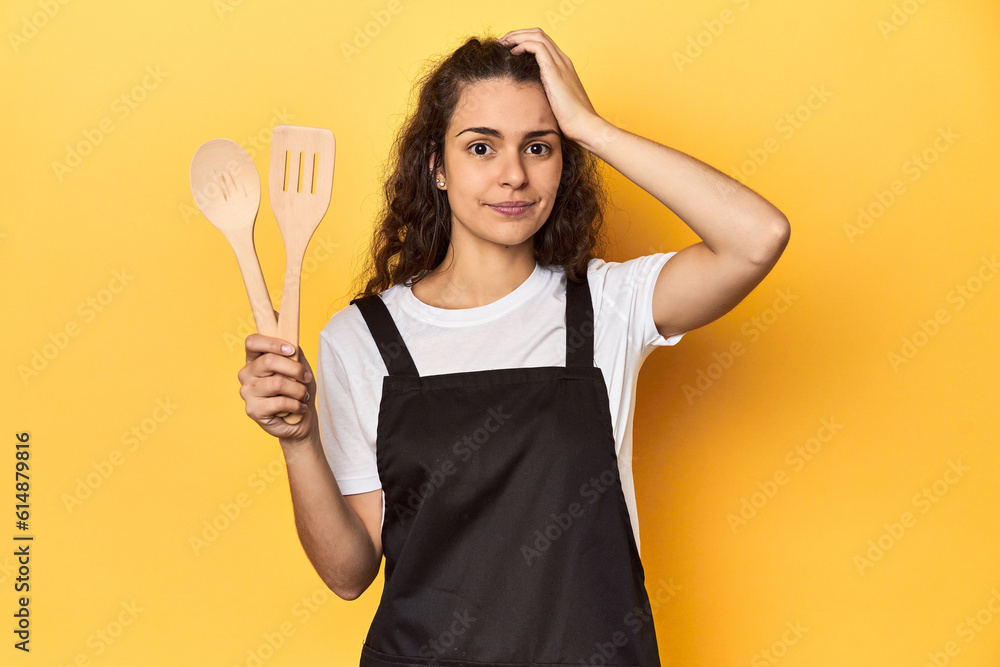 Woman with apron, wooden cooking utensils, yellow, being shocked, she has remembered important meeting. Woman with apron, wooden cooking utensils, yellow, being shocked, she has remembered important meeting.