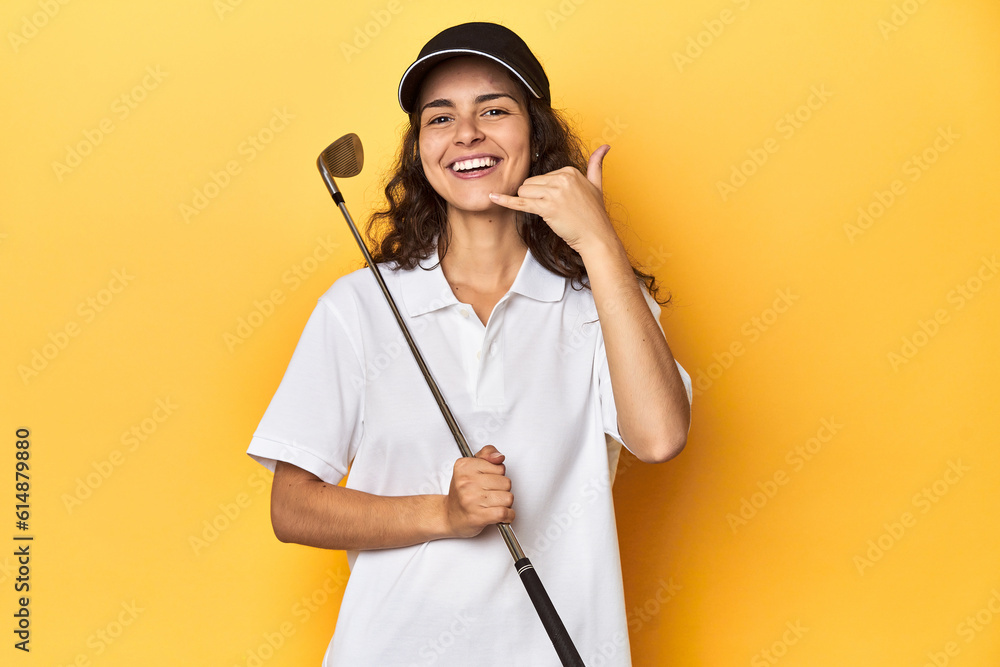Golfer woman with cap, golf polo, yellow studio, showing a mobile phone call gesture with fingers. Golfer woman with cap, golf polo, yellow studio, showing a mobile phone call gesture with fingers.