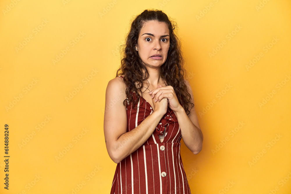 Fototapeta premium Young Caucasian woman, yellow studio background, scared and afraid.