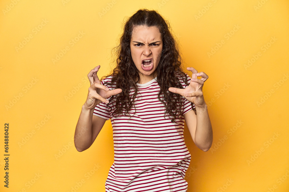Young Caucasian woman, yellow studio background, screaming with rage. Young Caucasian woman, yellow studio background, screaming with rage.