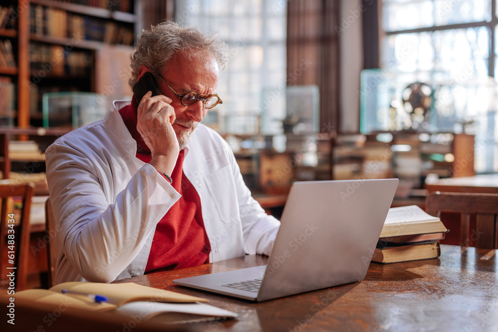 Medical professor using cellphone in library. Medical professor using cellphone in library.