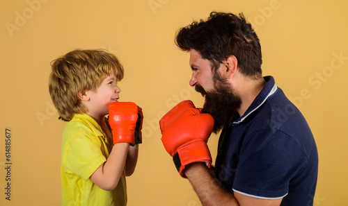Little kid boxer with coach at boxing training. Child with boxing trainer ready to sparring. Boy and trainer in boxing gloves. Child and coach in boxing ring. Sport lifestyle, fitness. Family workout. © Svitlana