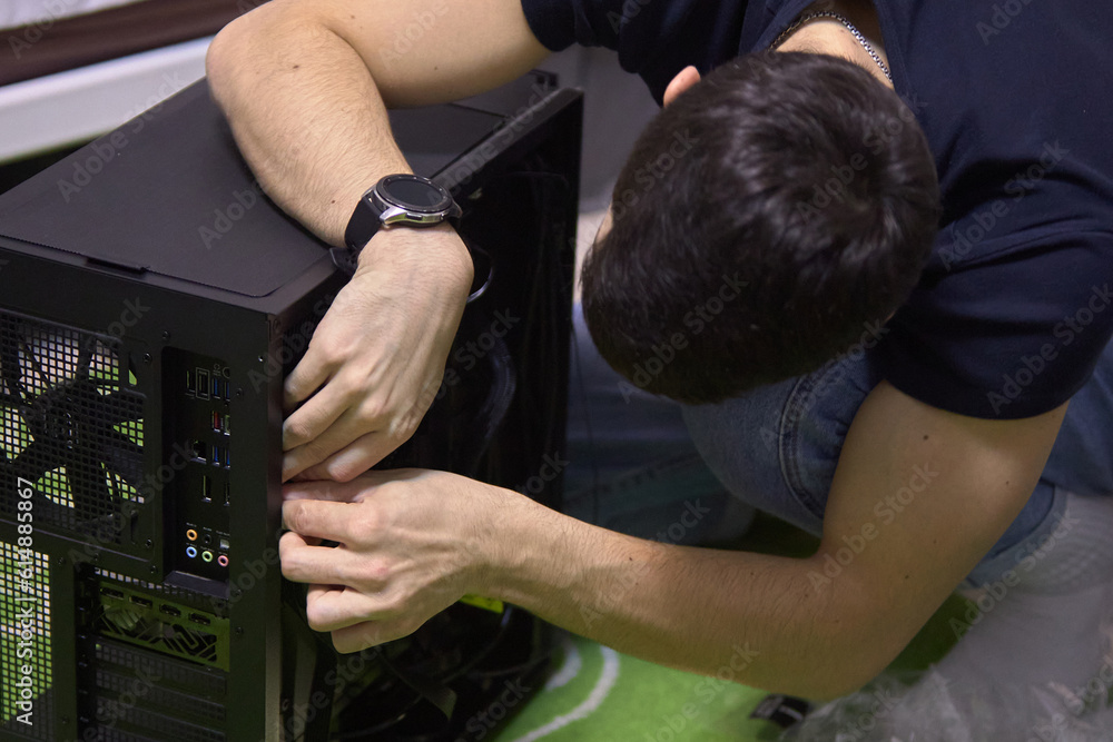 A young man, builds a new computer from components, cable management, the concept of assembling and repairing a computer A young man, builds a new computer from components, cable management, the concept of assembling and repairing a computer