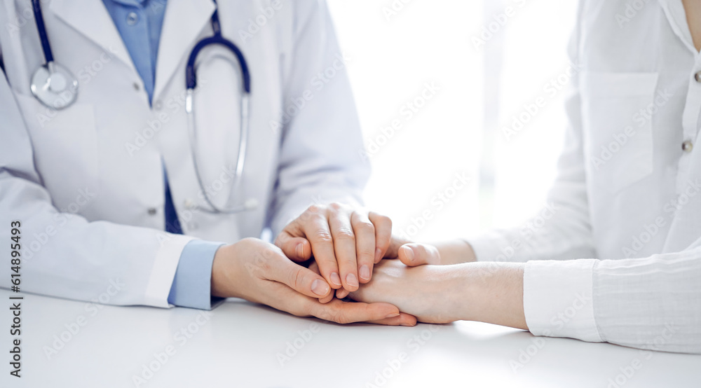 Doctor and patient sitting near each other at the table in clinic office. The focus is on female physician's hands reassuring woman, only hands, close up. Medicine concept Doctor and patient sitting near each other at the table in clinic office. The focus is on female physician's hands reassuring woman, only hands, close up. Medicine concept