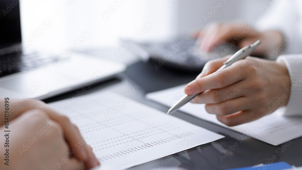 Woman accountant using a calculator and laptop computer while counting taxes for a client. Business audit concepts Woman accountant using a calculator and laptop computer while counting taxes for a client. Business audit concepts