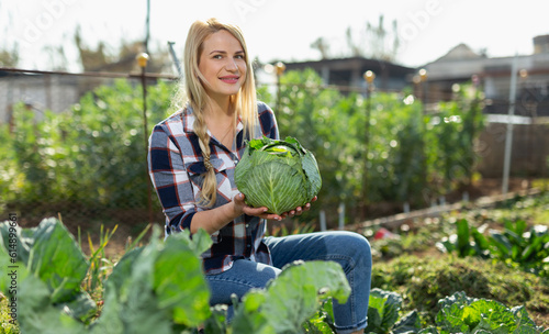 Portrait of positive woman working in homestead, satisfied with growing cabbage