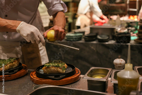 Um suculento filé de peixe perfeitamente grelhado, coberto com um irresistível molho pesto caseiro, é finalizado pelo talentoso chef com delicadas raspas de limão siciliano.  photo