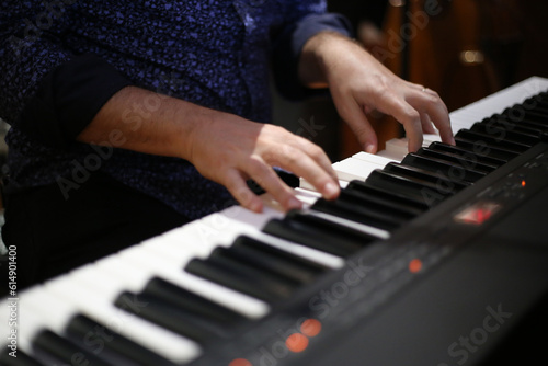 As mãos habilidosas do músico deslizam suavemente pelas teclas do teclado, criando uma melodia envolvente. Seus dedos ágeis e expressivos encontram cada nota com precisão, transmitindo emoção e paixão