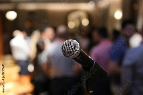 Um microfone posicionado em primeiro plano, aguardando ansiosamente o início do show em um evento social.