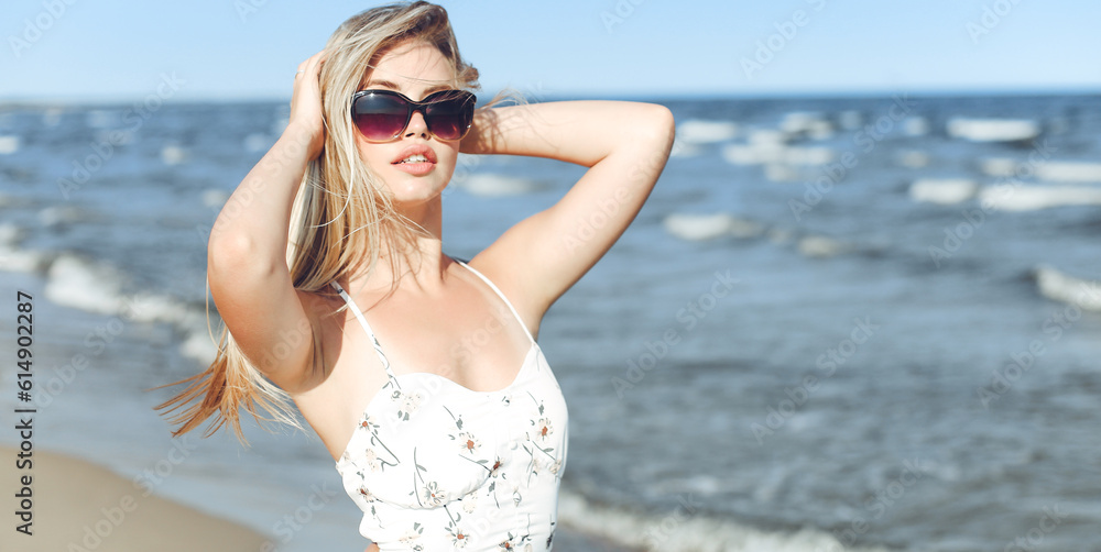 Happy blonde woman in free happiness bliss on ocean beach standing with sun glasses