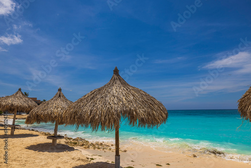 Beautiful view of beach with white sand, sun loungers and parasols against backdrop of turquoise water of Atlantic ocean. Aruba.