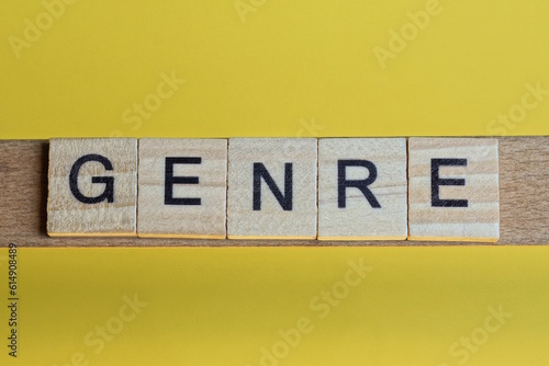 the word genre of gray small wooden letters lies on a yellow table photo