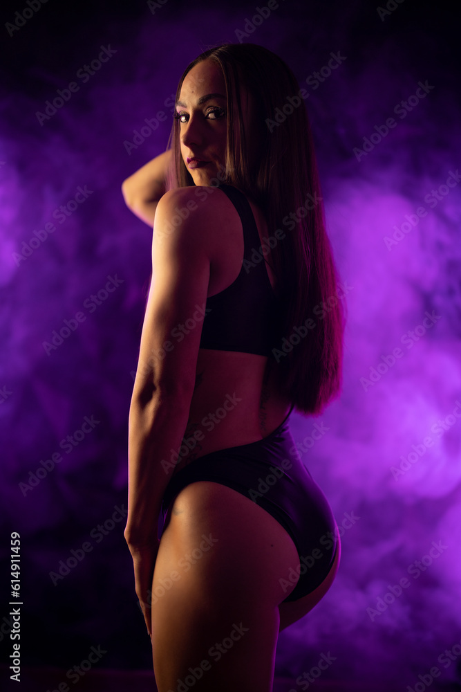 Fototapeta premium female fitness competitor posing in purple smoke