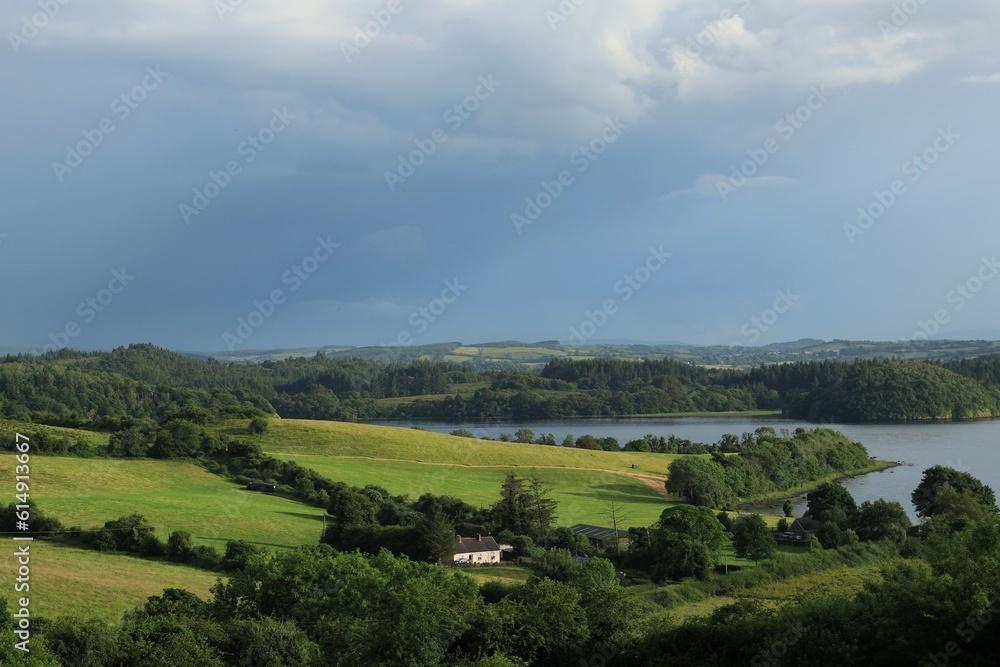 Landscape in rural County Leitrim, Ireland in summer featuring cottage home nestled between fields of meadow and pastures bordered by trees close to shores of Lough Gill Landscape in rural County Leitrim, Ireland in summer featuring cottage home nestled between fields of meadow and pastures bordered by trees close to shores of Lough Gill