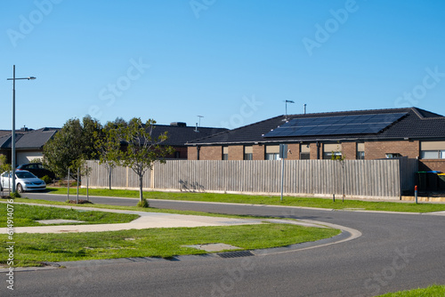 Background texture of a suburban street in an Australian neighbourhood with single storey residential house, family car parked on side of the asphalt road, grass nature stripe. Copy space