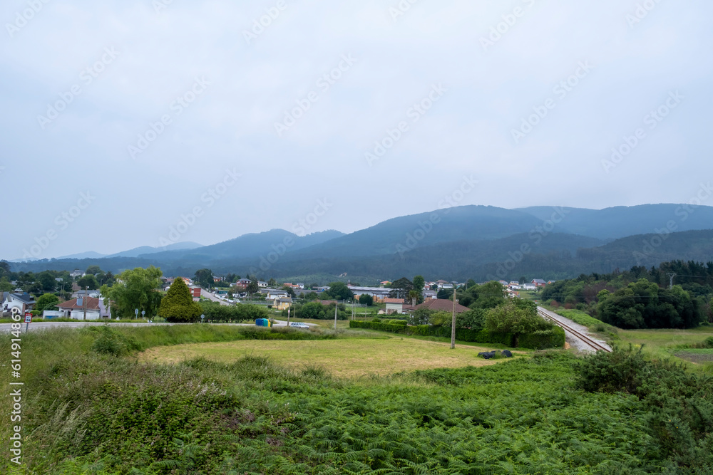 View of Cadaveu, Asturias, Spain. Train line and mountains on background. Cloudy day. View of Cadaveu, Asturias, Spain. Train line and mountains on background. Cloudy day.