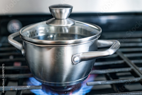 Steel saucepan with a glass lid on a gas stove.
