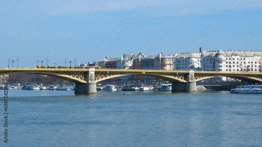 Train on chained bridge in budapest. A view of train driving on Margaret bridge over Danube against Budapest city in the day light.