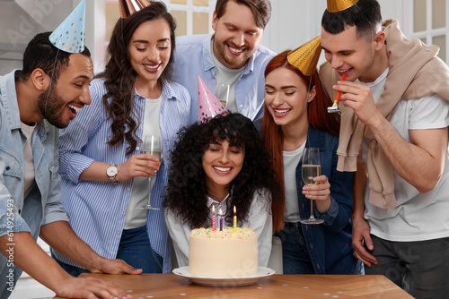 Happy friends with tasty cake celebrating birthday indoors