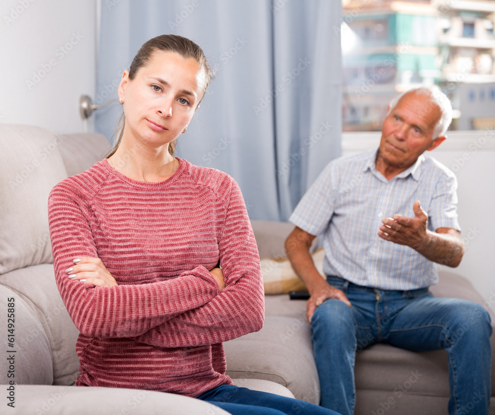 Portrait of unhappy woman sitting after quarrel with father at home interior