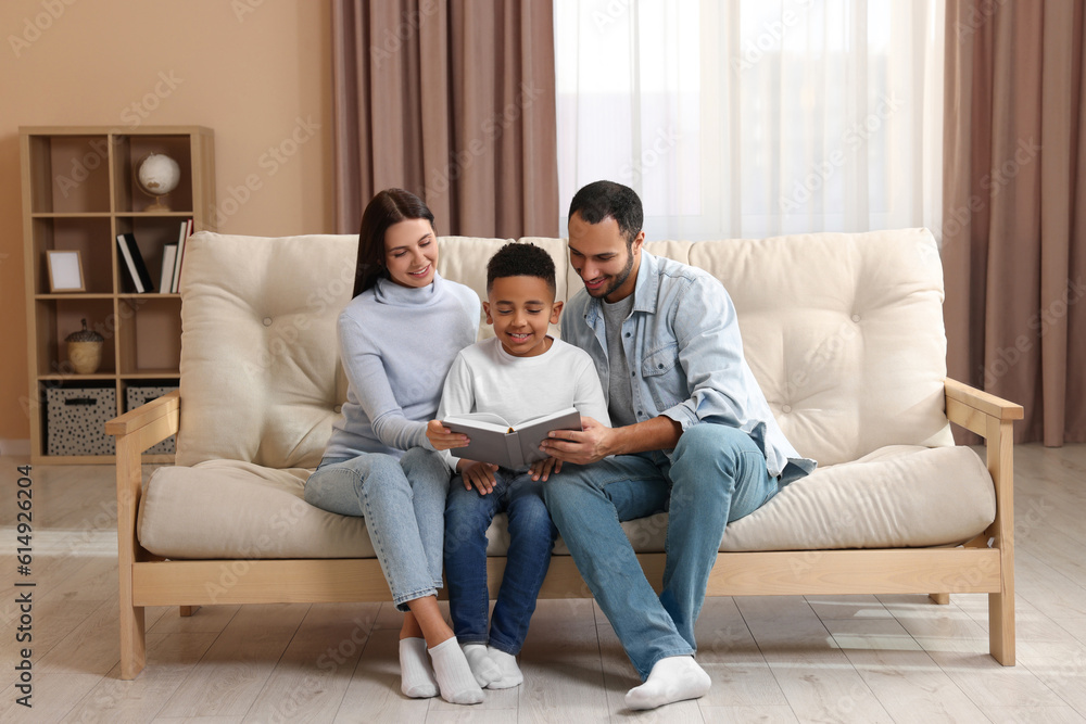 Happy international family reading book on sofa at home Happy international family reading book on sofa at home