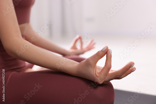 Woman in sportswear meditating indoors, closeup view