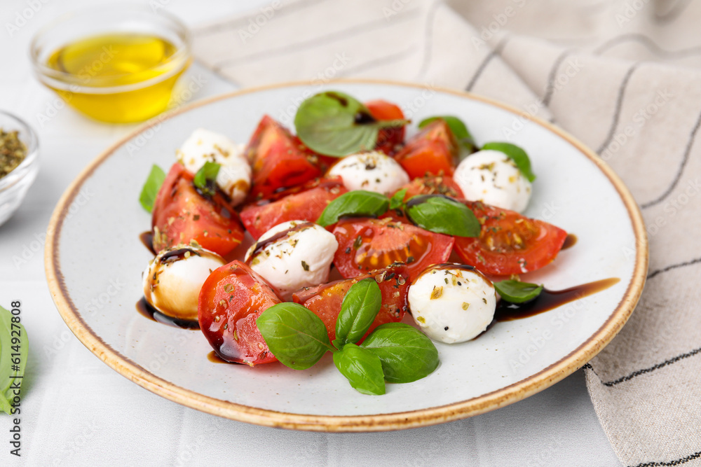 Tasty salad Caprese with mozarella balls, tomatoes, basil and sauce on white tiled table, closeup Tasty salad Caprese with mozarella balls, tomatoes, basil and sauce on white tiled table, closeup