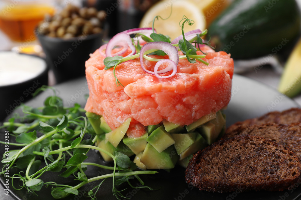 Tasty salmon tartare with avocado, microgreens and croutons on plate, closeup Tasty salmon tartare with avocado, microgreens and croutons on plate, closeup