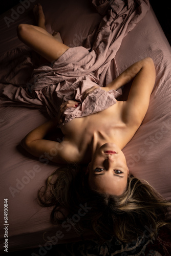 blonde female nude in pink sheet bed