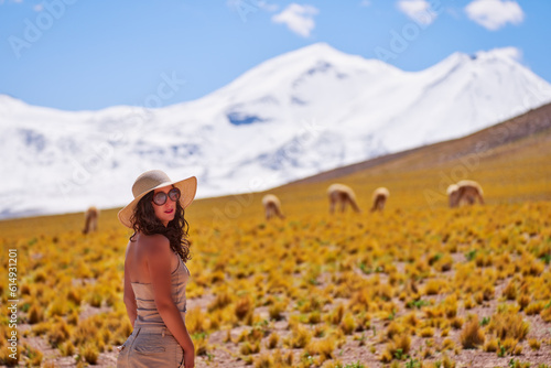 head shot portrait young Latin American woman outdoors in San Pedro de Atacama with Guanacos and snowy mountain in the background	 photo