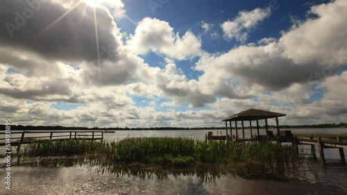 Time lapse of sun and clouds moving over lake and docks
