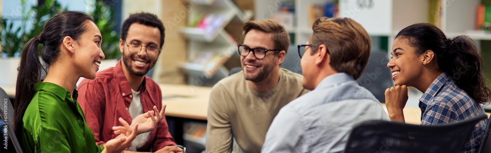 Obraz premium Creating success. Group of young happy multi racial business people communicating and sharing ideas while working together in the modern office