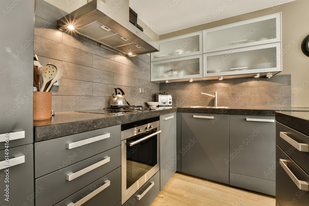 Fototapeta premium a modern kitchen with black counter tops and stainless appliances on the wall behind it is a sink, dishwasher and oven