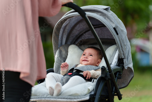 Obraz na plátne mother pushing happy infant baby stroller and walking in park