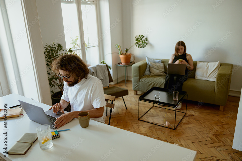 Married couple freelancers sit in living room with laptops and working from home office Married couple freelancers sit in living room with laptops and working from home office