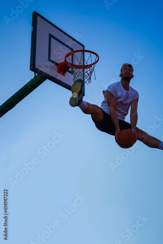 Man dunking in a basket over blue sky © iago
