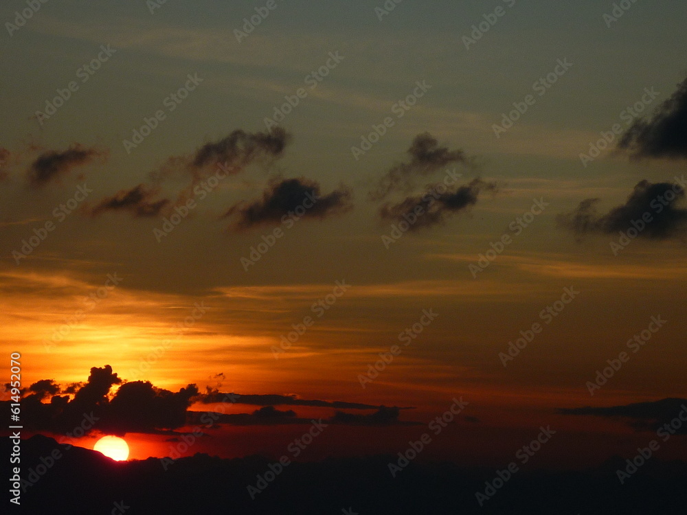 sunset in the mountains with an orange sky and black clouds sunset in the mountains with an orange sky and black clouds