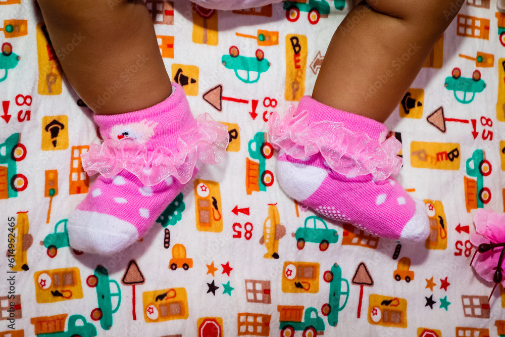 Closeup of legs of newborn baby wearing pink socks lying on bed