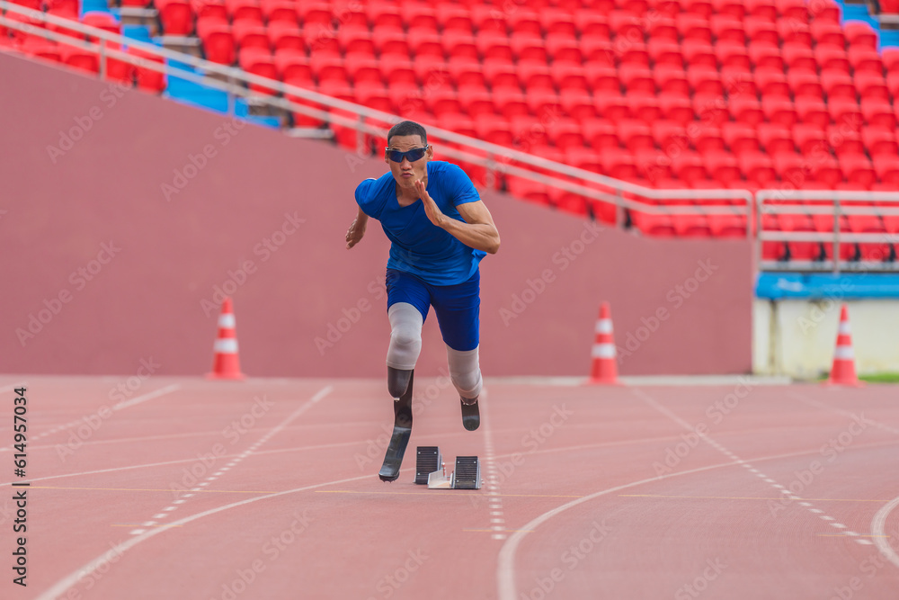 Asian male athlete, prosthetics user, sprints off from block start, powering his practice run on stadium track