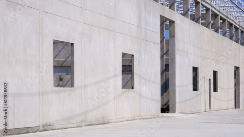 Perspective side view of concrete wall structure with roof beam of incomplete factory building in construction site