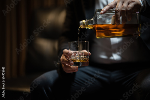 Businessman sitting Holding a Glass of Whiskey Drink Whiskey in the liquor store room
