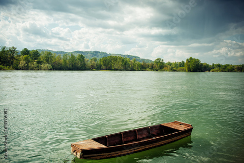 Fototapeta Naklejka Na Ścianę i Meble -  A small wooden fishing boat on the Drina River, in Serbia on a cloudy but sunny day. Reflection of sunlight in turquoise water