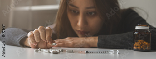 Obraz na plátne Anti drugs, drug addict asian young woman hand holding pills, medicament with narcotic syringe on table at home, abuse overdose