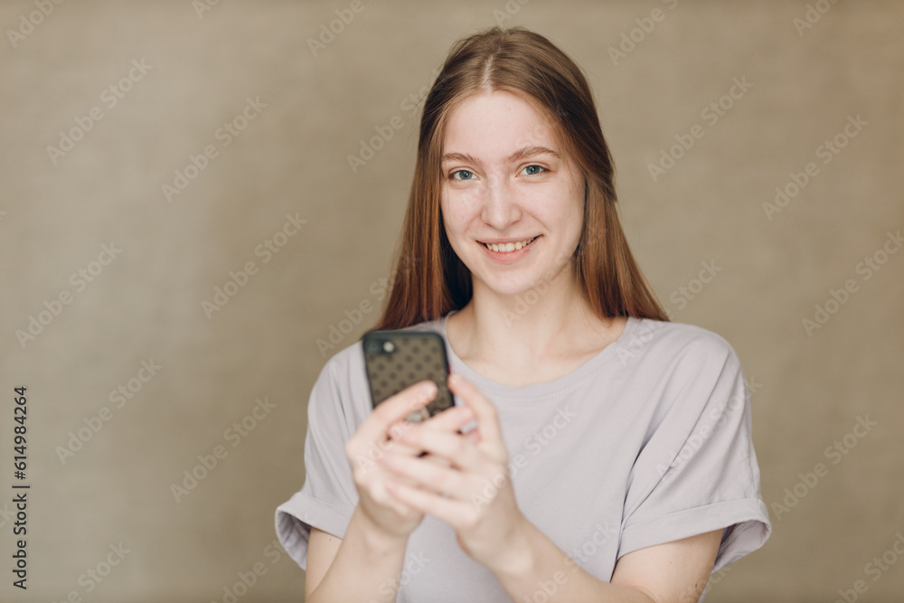 Young woman using mobile phone at brown background Young woman using mobile phone at brown background