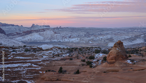 Soft pink clouds hang over the winter desert in arches national park.